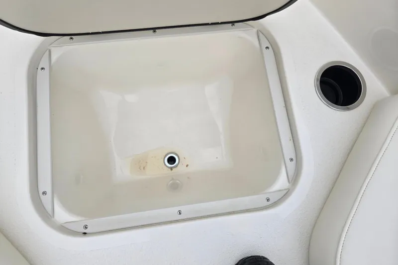 Slide: The Image of 2016 Stingray 198 RX boat storage compartment with cup holder, white interior. - 19