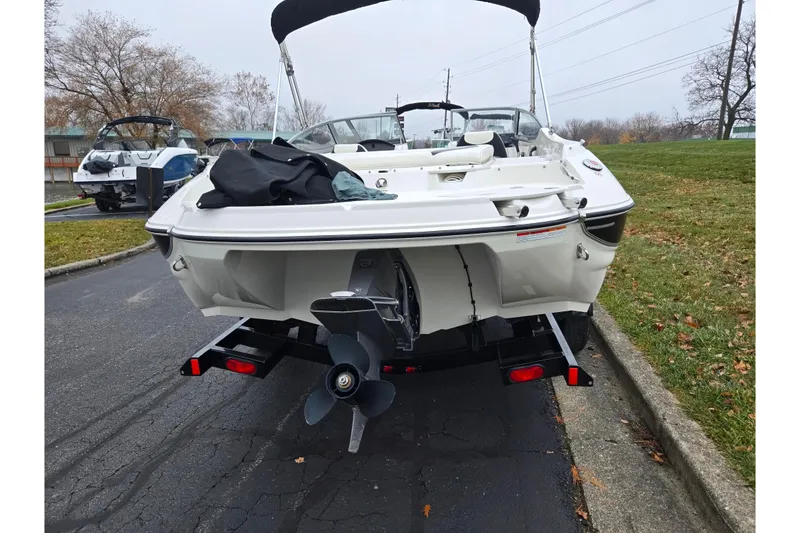 Slide: The Image of 2016 Stingray 198 RX boat on trailer, parked on a paved road with grass nearby. - 2