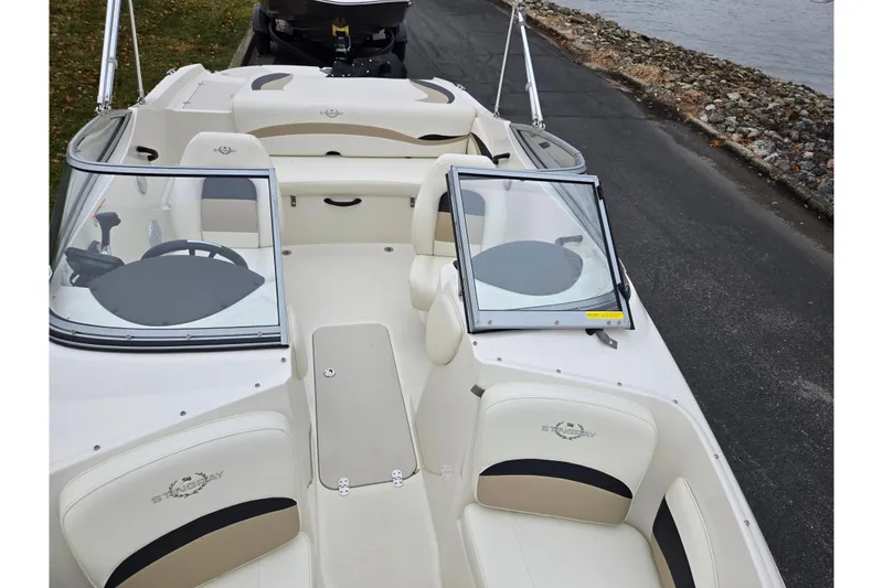 Slide: The Image of 2016 Stingray 198 RX boat interior with open windshield, parked near water. - 21