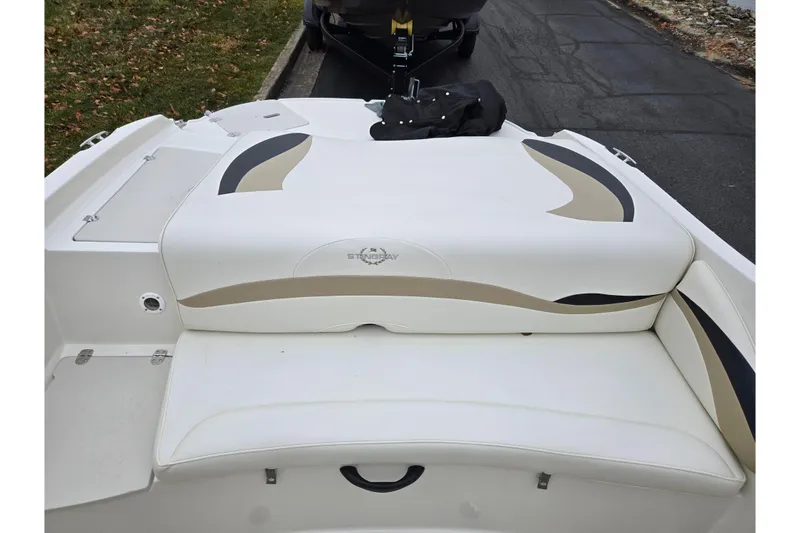 Slide: The Image of 2016 Stingray 198 RX boat with white and beige seating, parked on pavement. - 23