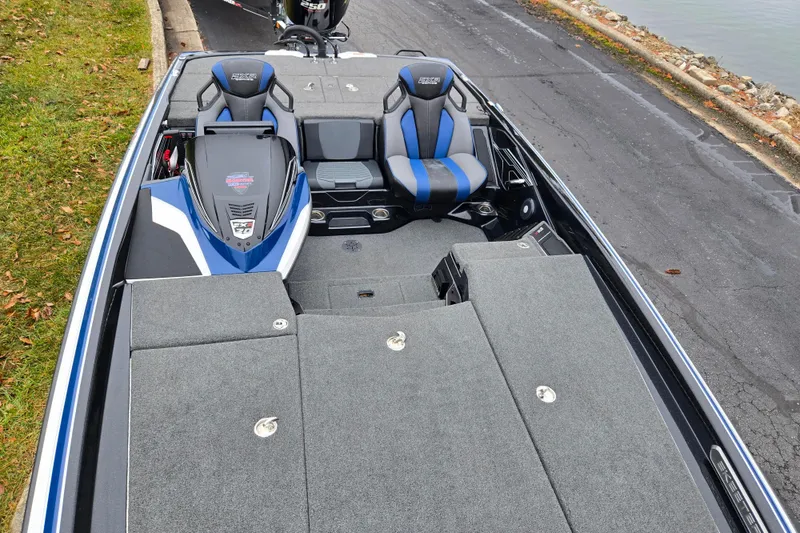 Slide: The Image of 2021 Skeeter FXR20 boat interior with blue and gray seating, docked by a lakeside. - 11