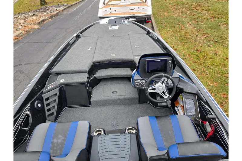 Slide: The Image of 2021 Skeeter FXR20 boat interior with steering console and seating, parked on a road. - 17