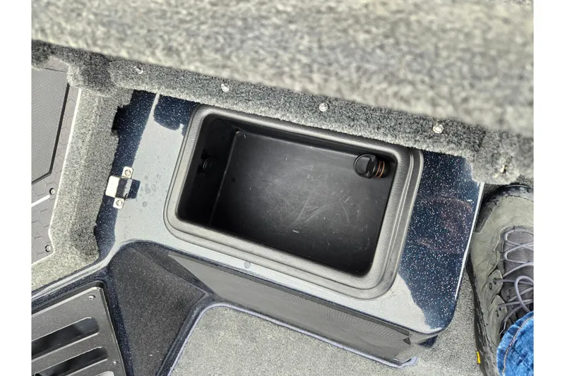 Slide: The Image of 2021 Skeeter FXR20 boat storage compartment with carpeted interior and foot visible. - 23