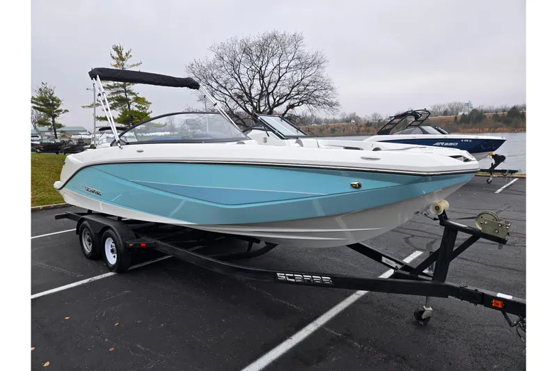 Slide: The Image of 2021 Scarab 255 ID boat on trailer, parked near a lake. - 8