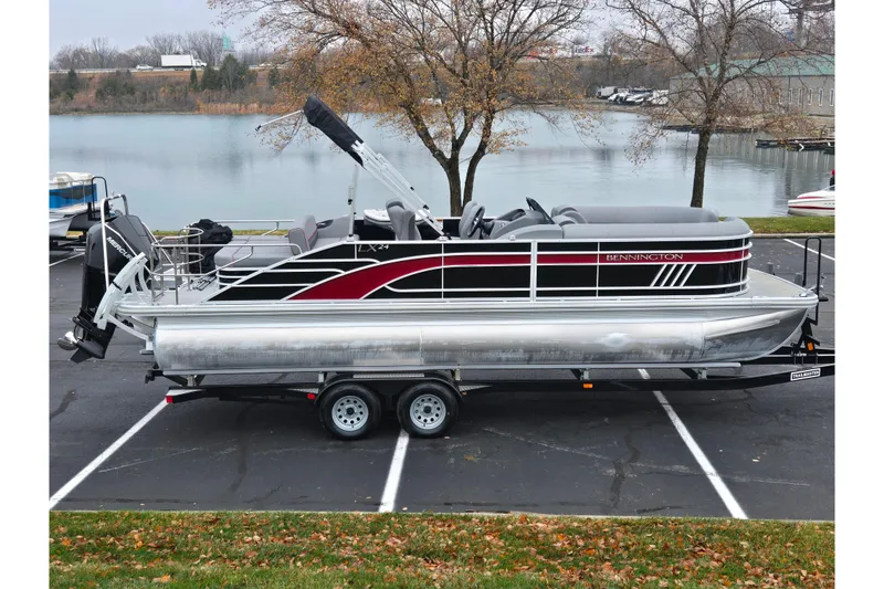 The Image of 2022 Bennington LX 24 Swingback pontoon boat on trailer by a lake. - 0