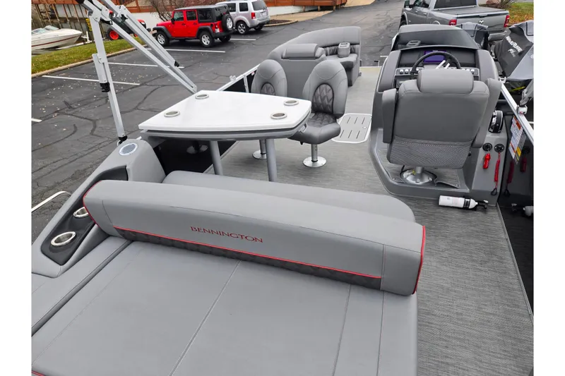 Slide: The Image of 2022 Bennington LX 24 Swingback boat interior with seating and table, parked in a lot. - 19
