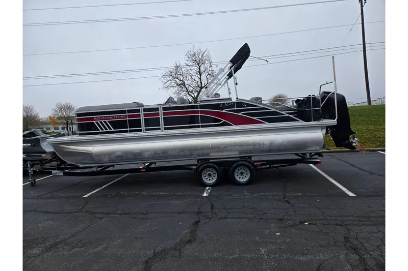 Slide: The Image of 2022 Bennington LX 24 Swingback pontoon boat on a trailer in a parking lot. - 4
