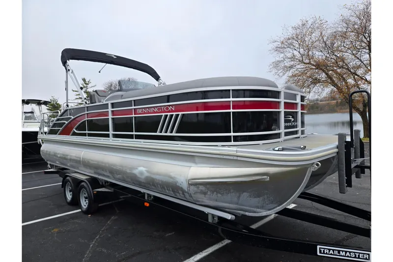Slide: The Image of 2022 Bennington LX 24 Swingback pontoon boat on a trailer by a lake. - 8