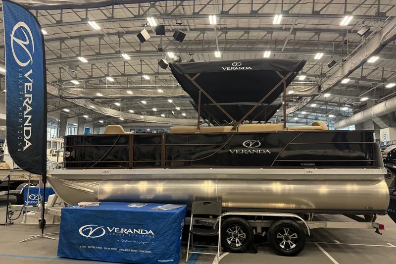 The Image of 2025 Veranda Fish VF20F4 pontoon boat displayed indoors with branded banners and table. - 0