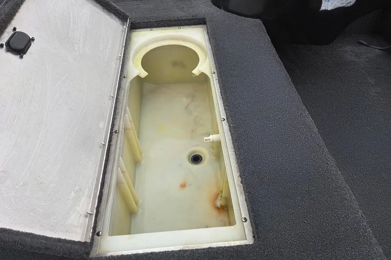 Slide: The Image of Open storage compartment in 2018 Lowe Stinger 195C boat, featuring a drain hole. - 11