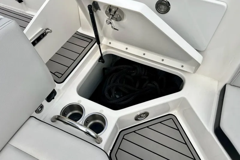 Slide: The Image of 2023 Searay SPX230 boat storage compartment with cup holders and rope. - 29