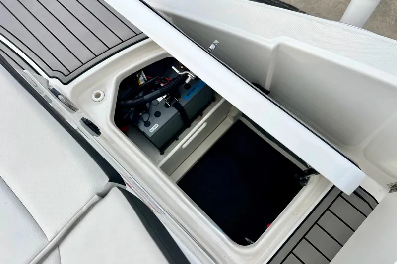 Slide: The Image of 2023 Searay SPX230 boat storage compartment with battery, open lid view. - 33