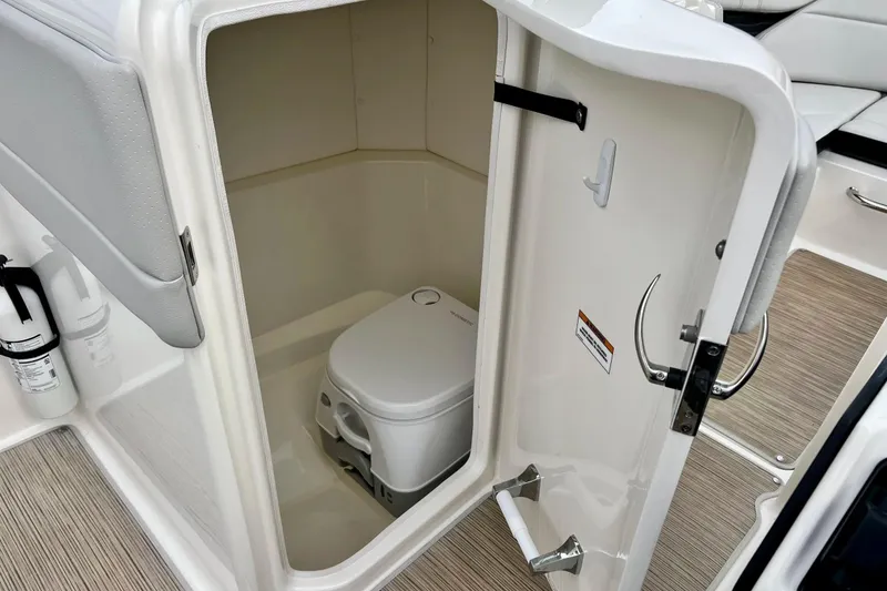 Slide: The Image of 2023 Searay SPX230 boat interior with compact toilet and storage area. - 45