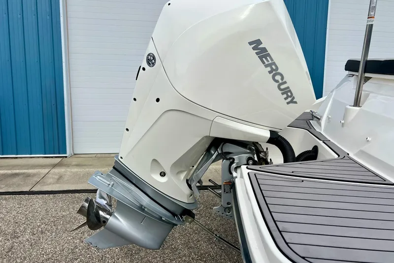 Slide: The Image of 2023 Searay SPX230 boat with Mercury outboard motor, docked near blue building. - 7