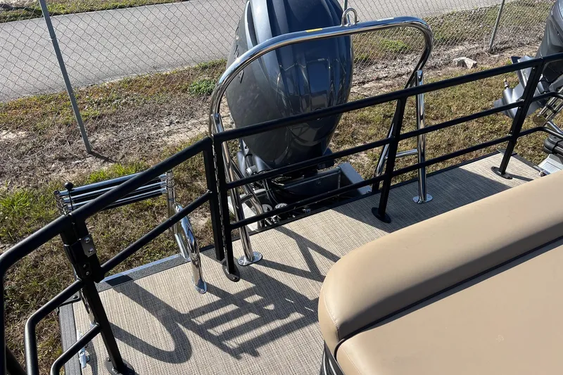 Slide: The Image of 2026 Sylvan Mirage 822 CLZ boat with motor and seating, near a chain-link fence. - 21