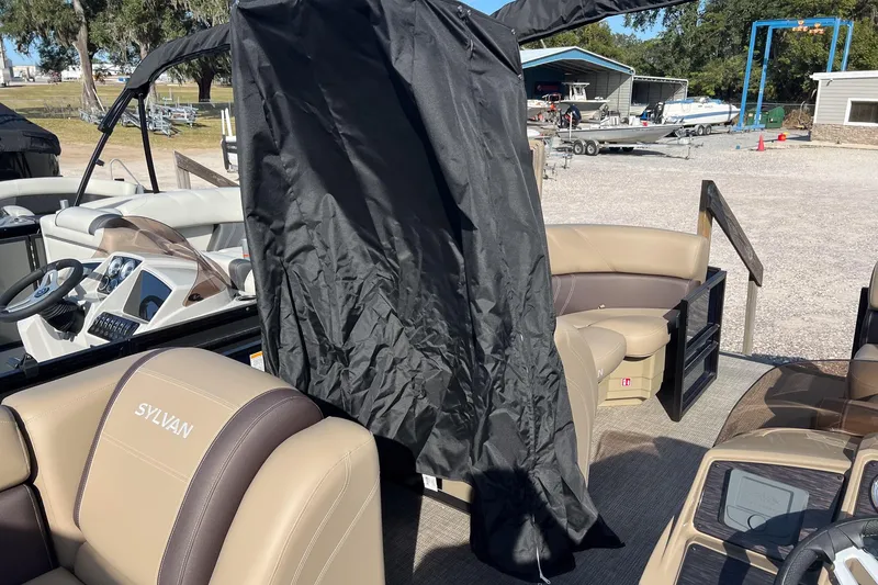 Slide: The Image of 2026 Sylvan Mirage 822 CLZ pontoon boat interior with beige seating and black cover. - 23
