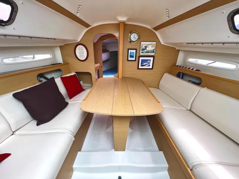 Slide: The Image of Interior of a 2014 Beneteau FIRST 25 S yacht with wooden table and white seating. - 17