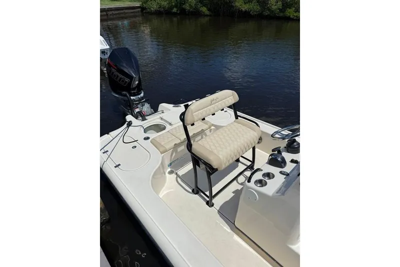 Slide: The Image of 2017 Yellowfin 24 Bay CE boat with cushioned seating and outboard motor on calm water. - 21