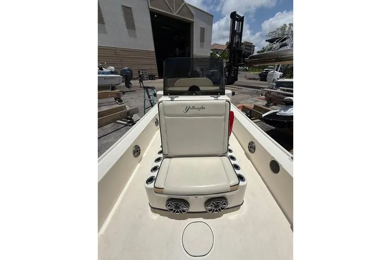 Slide: The Image of 2017 Yellowfin 24 Bay CE boat interior with seating and speakers in a marina setting. - 6