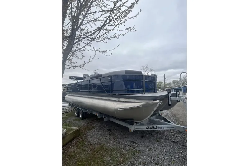 Slide: The Image of 2025 Veranda Relax VR 25 VLC pontoon boat on trailer, parked outdoors. - 2