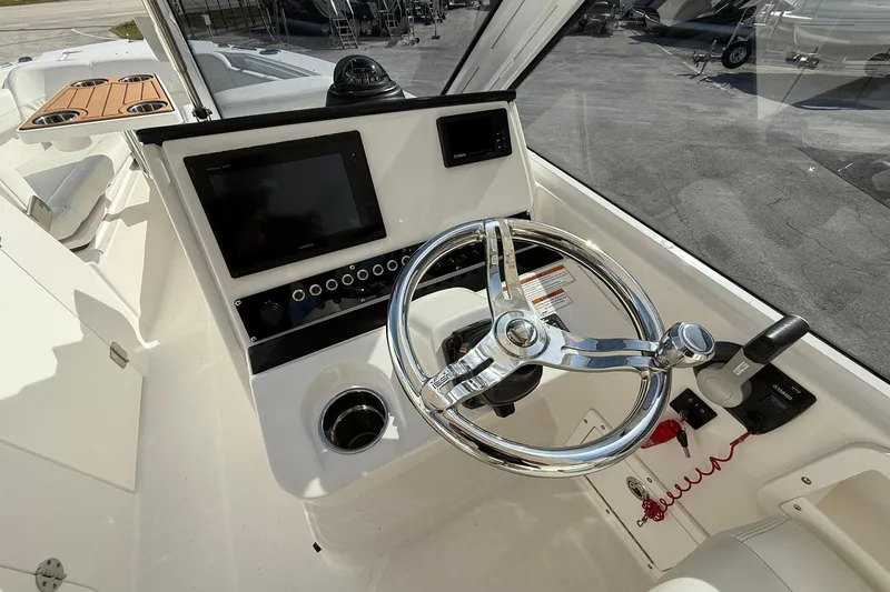 Slide: The Image of 2019 Edgewater 230CX Crossover boat helm with steering wheel and control panel. - 14