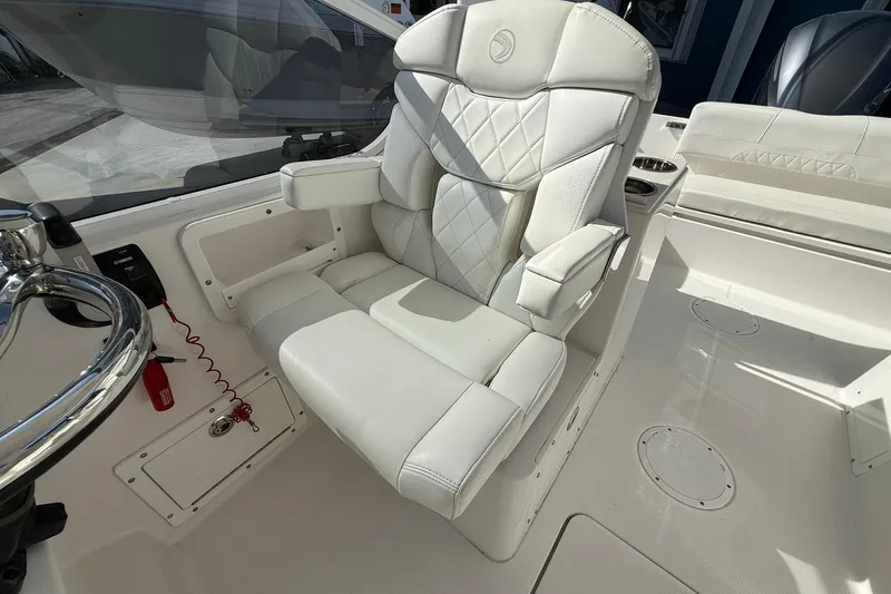 Slide: The Image of 2019 Edgewater 230CX Crossover boat interior with white captain's chair and steering wheel. - 17