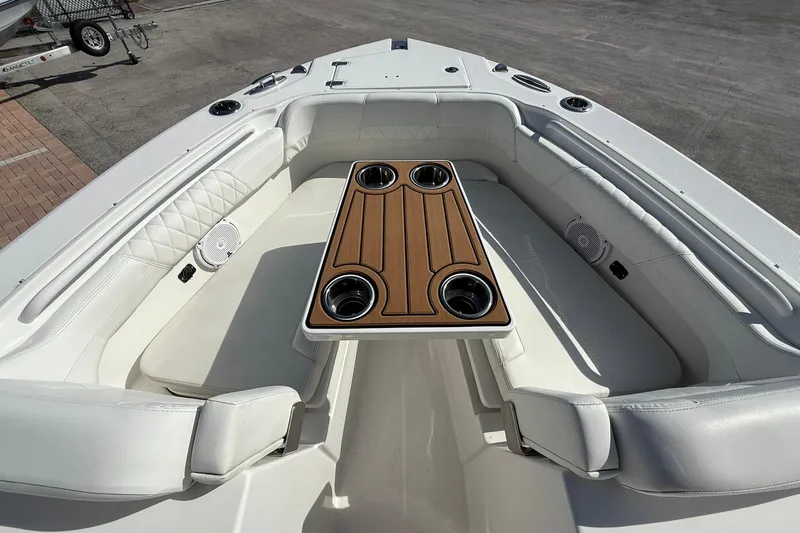 Slide: The Image of 2019 Edgewater 230CX Crossover boat interior with cushioned seating and wooden table. - 19