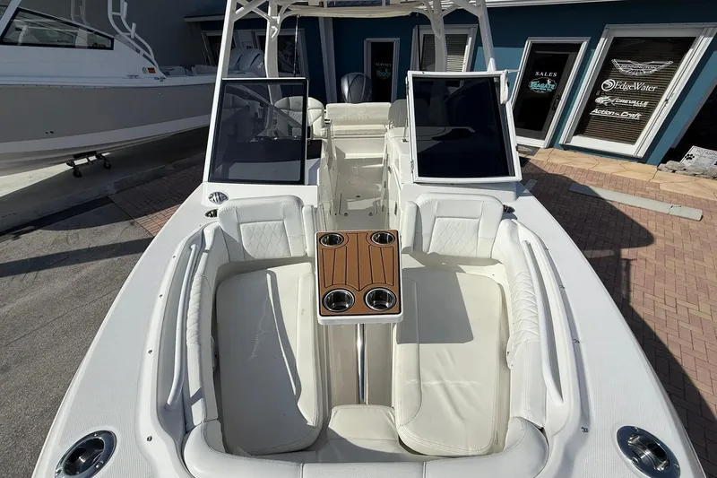 Slide: The Image of 2019 Edgewater 230CX Crossover boat interior with white seating and wooden table. - 20