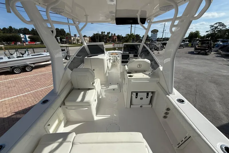 Slide: The Image of 2019 Edgewater 230CX Crossover boat interior with seating and helm, parked outdoors. - 6