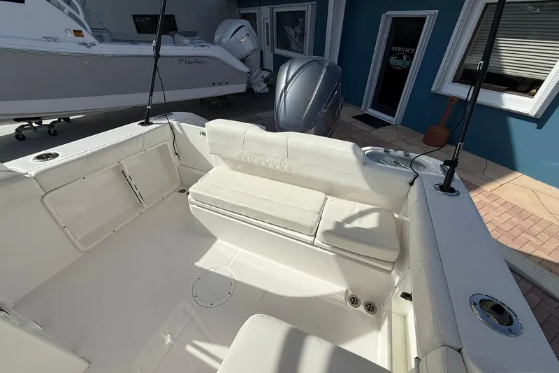 Slide: The Image of 2019 Edgewater 230CX Crossover boat interior with white seating and fishing rod holders. - 9
