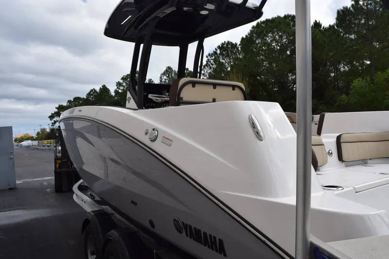 Slide: The Image of 2026 Yamaha Boats 255 FSH Sport H, sleek design, parked outdoors, rear view. - 6