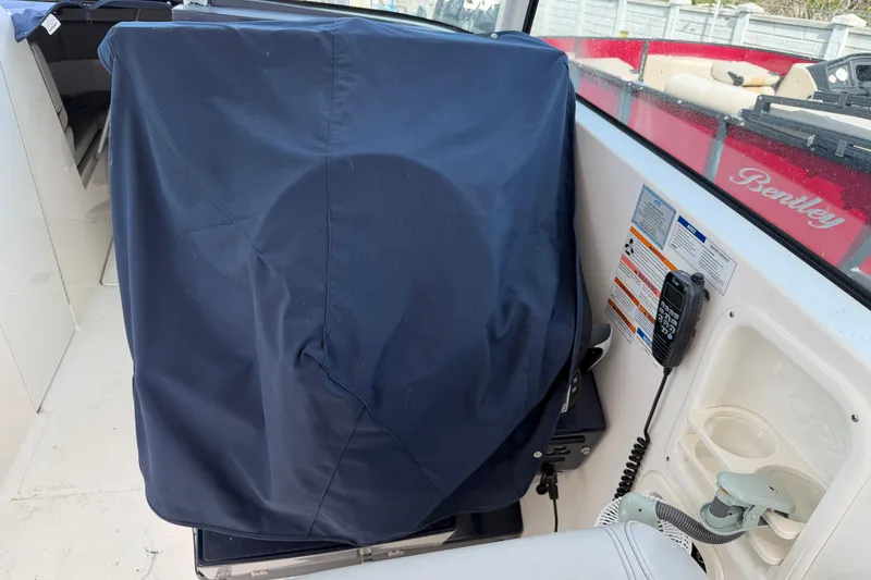Slide: The Image of 2023 Pursuit DC 295 Dual Console boat interior with covered equipment and communication device. - 11