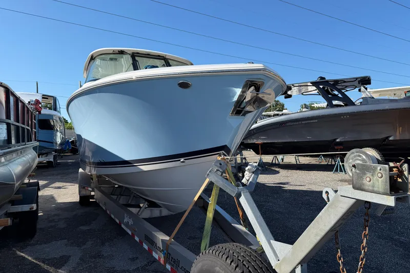 Slide: The Image of 2023 Pursuit DC 295 Dual Console boat on trailer in a marina setting. - 2
