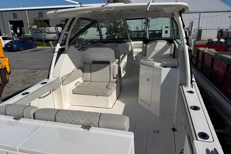 Slide: The Image of 2023 Pursuit DC 295 Dual Console boat interior with seating and storage, docked outdoors. - 6