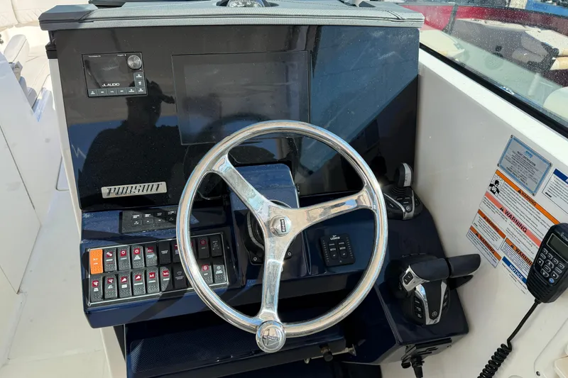 Slide: The Image of 2023 Pursuit DC 295 Dual Console boat dashboard with steering wheel and controls. - 9