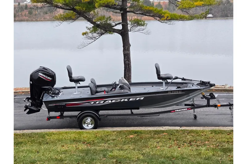 The Image of 2022 Tracker Pro Team 175 TF fishing boat on trailer by a lake. - 0