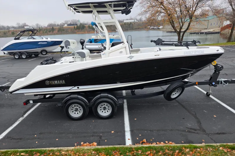 Slide: The Image of 2022 Yamaha Boats 210 FSH Sport on trailer in parking lot near lake. - 10