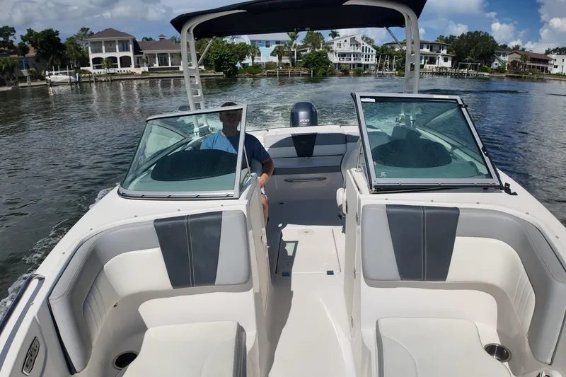 Slide: The Image of 2020 Chaparral 23 SSi boat cruising on a scenic waterway with waterfront homes. - 11