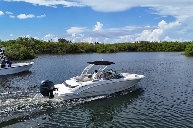 Slide: The Image of 2020 Chaparral 23 SSi boat cruising on a scenic waterway under a clear blue sky. - 2