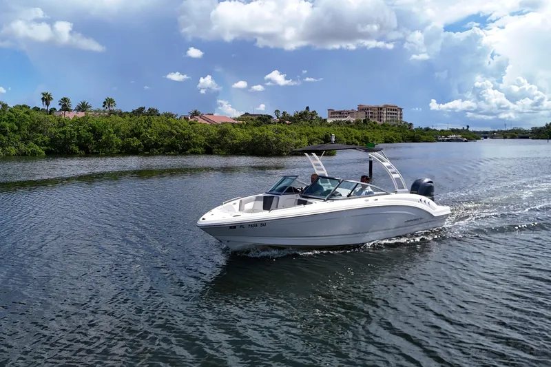 Slide: The Image of 2020 Chaparral 23 SSi boat cruising on a scenic waterway under a partly cloudy sky. - 3