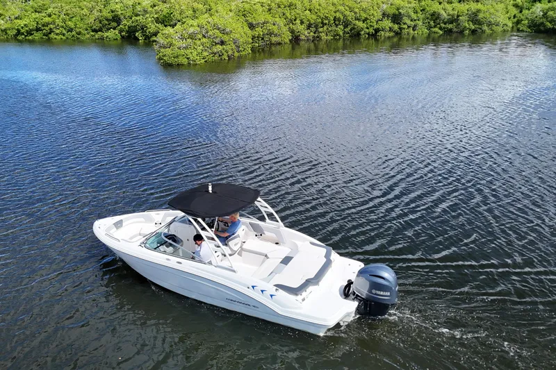 Slide: The Image of 2020 Chaparral 23 SSi boat cruising on a calm lake with lush greenery. - 5