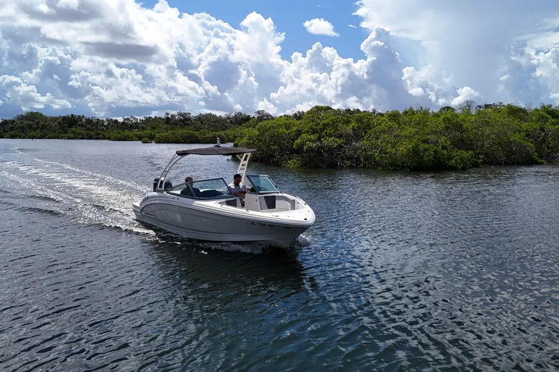 Slide: The Image of 2020 Chaparral 23 SSi boat cruising on a scenic waterway under a cloudy sky. - 6