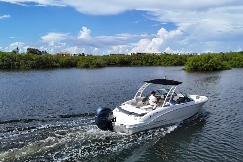 Slide: The Image of 2020 Chaparral 23 SSi boat cruising on a scenic river under a clear blue sky. - 8