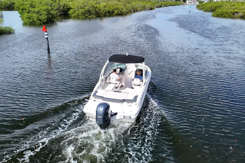 Slide: The Image of 2020 Chaparral 23 SSi boat cruising through a scenic waterway with lush greenery. - 9
