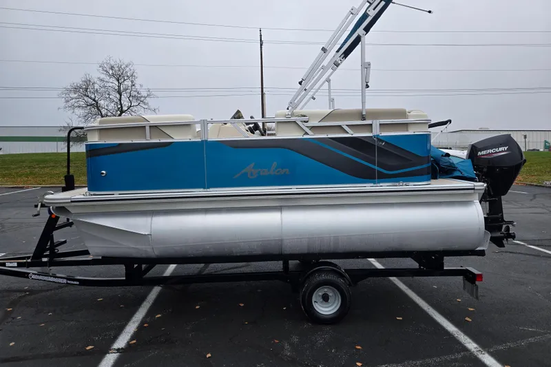 Slide: The Image of 2023 Avalon Venture CR 1575 pontoon boat on trailer, featuring a blue and silver design. - 4