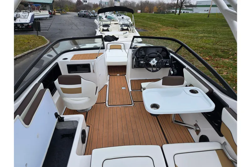 Slide: The Image of 2023 Yamaha Boats 195S interior with seating, steering wheel, and table on a wooden deck. - 10
