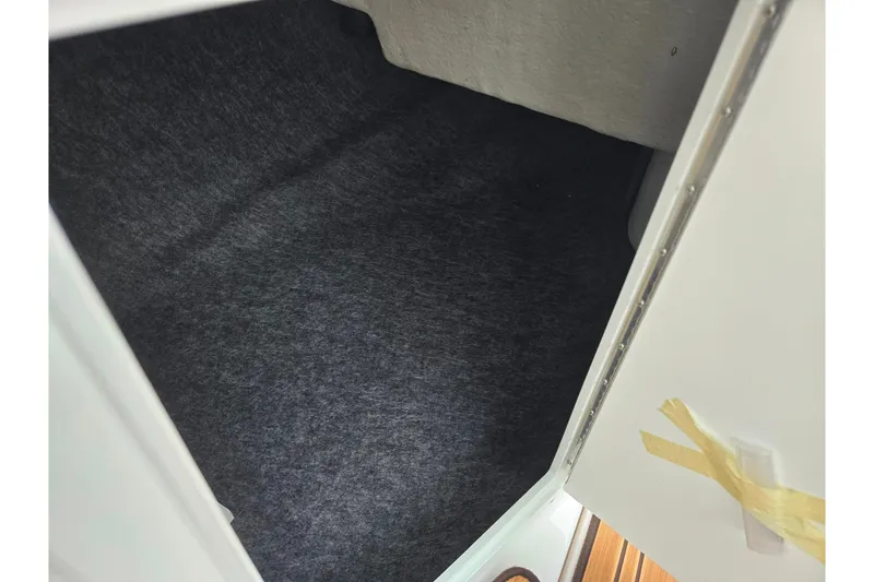 Slide: The Image of Interior storage compartment of 2023 Yamaha Boats 195S, featuring carpeted flooring. - 14