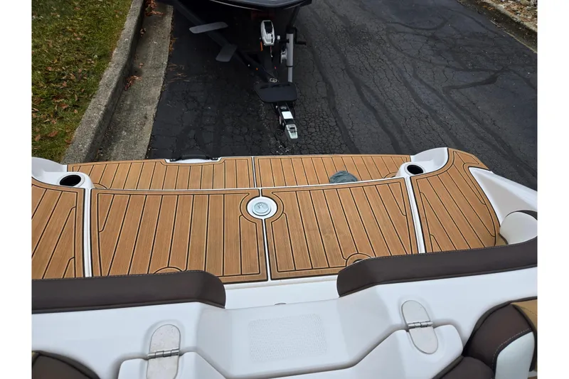 Slide: The Image of 2023 Yamaha Boats 195S swim platform with teak-style decking, parked on pavement. - 22