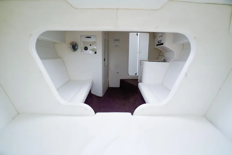 Slide: The Image of Interior of 2000 Active Thunder 32 boat, featuring white seating and compact kitchenette. - 18