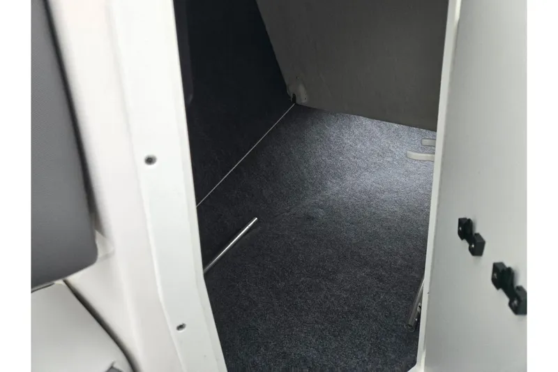 Slide: The Image of Interior storage compartment of 2025 Yamaha Boats AR220, featuring carpeted flooring. - 16